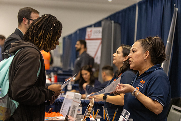 Students speaking with university department staff at a job fair